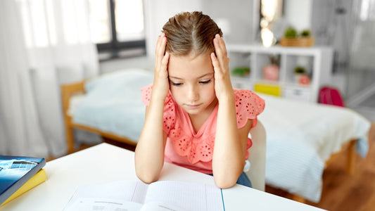 Young girl struggling to concentrate on homework, showing possible signs of childhood ADHD or anxiety.